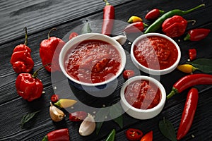 Spicy hot sweet chili sauce with mix of chilli pepper, garlic and tomatoes on rustic wooden background photo