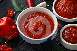 Spicy hot sweet chili sauce with mix of chilli pepper, garlic and tomatoes on rustic wooden background