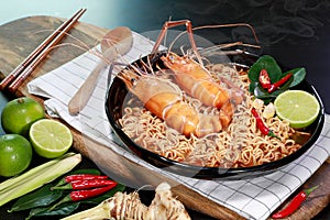 Spicy instant noodles soup with rivers shrimp on top, on black table background with smoke. Tom Yum Kung name in Thailand Foods
