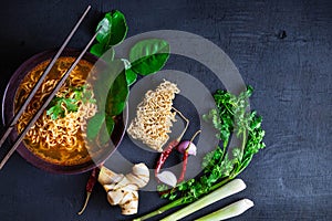 Spicy instant noodles soup And vegetables on a black background