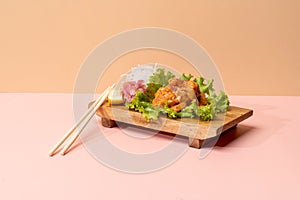 SPICY MAGURO SASHIMI with salad leaves and chopsticks isolated on wooden cutting board side view fast food