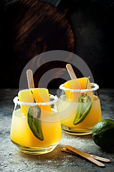 Spicy mango popsicle margarita cocktail with jalapeno and lime. Mexican alcoholic drink for Cinco de mayo party.