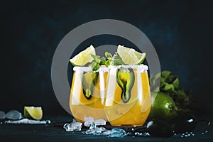 Spicy margarita cocktail with tequila, mango juice, jalapeno pepper, lime and salt, blue background, copy space