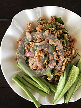 Spicy minced pork salad with green beans on white plate, Thai food