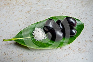 Spicy mixed salt with some black java plum fruit in the green leaves. A way to eat ripe cesium camini fruit by hand. 4k closeup