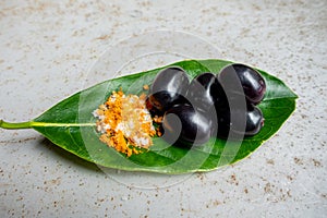 Spicy mixed salt with some black java plum fruit in the green leaves. A way to eat ripe cesium camini fruit by hand. 4k closeup