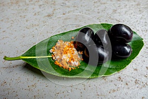 Spicy mixed salt with some black java plum fruit in the green leaves. A way to eat ripe cesium camini fruit by hand. 4k closeup