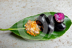 Spicy mixed salt with some black java plum fruit in the green leaves. A way to eat ripe cesium camini fruit by hand. 4k closeup