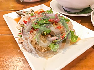 Spicy Mung Bean Noodle and seafood salad on wood table in restaurant.Spicy and delicious Thai food