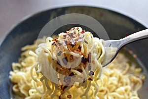 Spicy noodle soup on fork in a bowl.