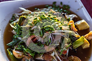 The Spicy papaya salad called `Somtum` in Thai on wooden table with sun light ray