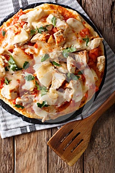 Spicy pizza with chicken, tomatoes, buffalo sauce and cheese close-up. vertical top view photo