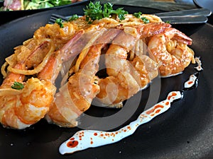 Spicy prawn spaghetti on black plate served in restaurant for dinner