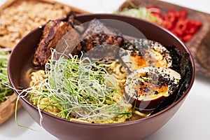 Spicy ramen with beef, egg and microgreen in bowl photo