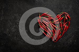 Spicy red chili pepper in the shape of a heart on a dark stone background