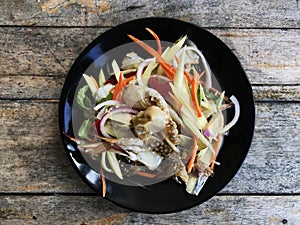 Spicy salad with crab in black dish on the vintage table