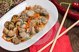 Spicy salad of mushrooms and carrots in Korean. Top view. Close-up. Wooden rustic background.