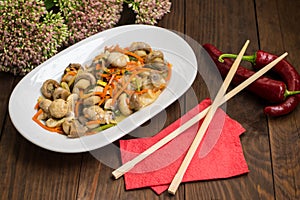 Spicy salad of mushrooms and carrots in Korean. Top view. Close-up. Wooden rustic background.