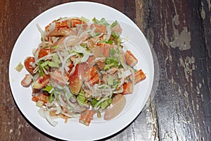 Spicy salmon and crab stick or kanikama salad with vegetable in white plate on wooden table.