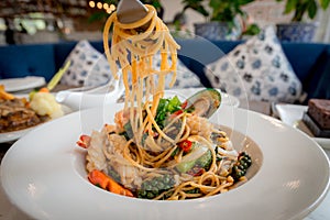 Spicy Seafood Spaghetti stir fried Pad Cha rolled in the fork on white dish of luxury restaurant