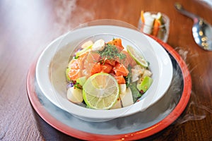 Spicy sliced salmon with fruit salad in white ceramic bowl