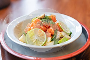 Spicy sliced salmon with fruit salad in white ceramic bowl