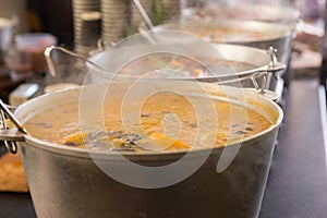 Spicy soup in large cauldrons with ladle inside at outdoor food