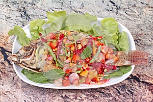 Spicy and sour fried Tilapia Salad with baby tamarind leaves .