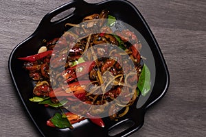 Spicy stir-fried mussels in a black dish.Thai food