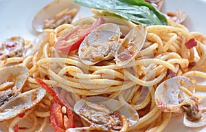 spicy stir fried spaghetti clams with pepper and basil leaf on plate