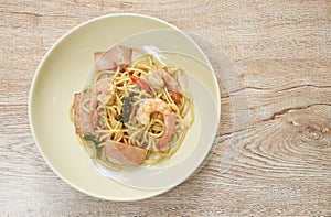 Spicy stir fried spaghetti shrimp with slice ham pork and basil leaf on plate