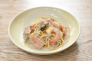 Spicy stir fried spaghetti shrimp with slice ham pork and basil leaf on plate