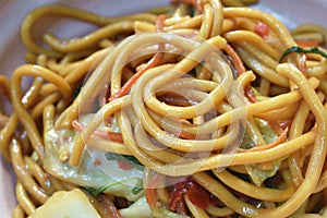 Spicy stir fried vegetarian yakisoba Japanese noodles with cabbage and basil leaf on bowl