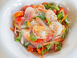 Spicy strawberries salad with fresh shrimps on white dish