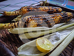 Spicy sweet corn burn in fire with lemon and salt in a wood tray from different angles