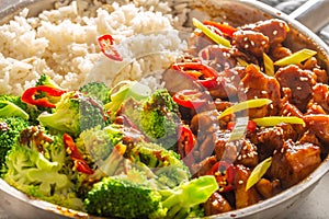 Spicy teriyaki chicken with steamed broccoli and rice in a pot