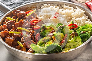 Spicy teriyaki chicken with steamed broccoli and rice in a pot