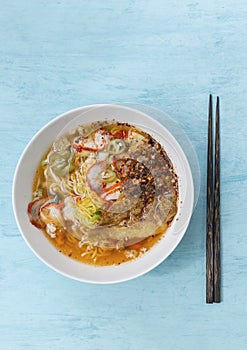 Spicy Thai style egg noodle soup with roasted pork in white bowl