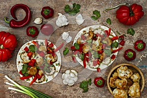 Spicy veggies tacos with roasted cauliflower, zucchini and tomato salsa on rustic wooden cutting board.