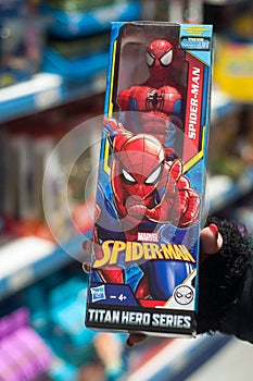 Spider man figurine in hand of woman in a toys store supermarket