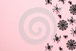 Spider webs and spiders on pastel pink background. Flat lay, top view, copy space. Happy Halloween holiday concept