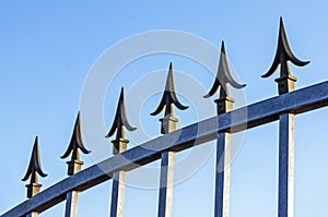 Spikes on Galvanised Gate Against Blue Sky
