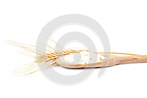 Spikes of wheat and flour in a wooden spoon.