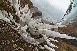 Spiky, icy stalagmites created from the roof of a mountain next to the Kvernufoss waterfall, seen from a vantage point as if it