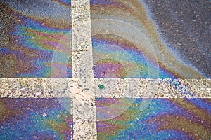 Spill of oil, gasoline or oil on wet asphalt with parking and dividing lines