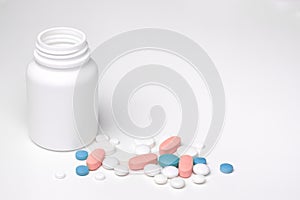 Spilled blue white pink pills from open prescription medication plastic white bottle