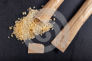 Spilled cane sugar from a small sachet. Preparation for sweetening beverages in a small package