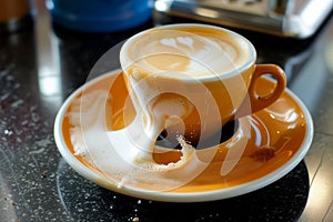 spilled cappuccino with froth on a saucer