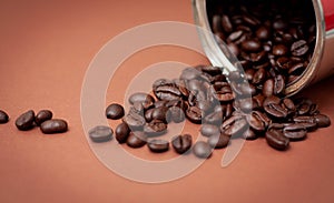 Spilled coffee beans on brown background