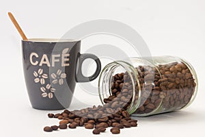 Spilled coffee beans from jar and cup with wooden spoon